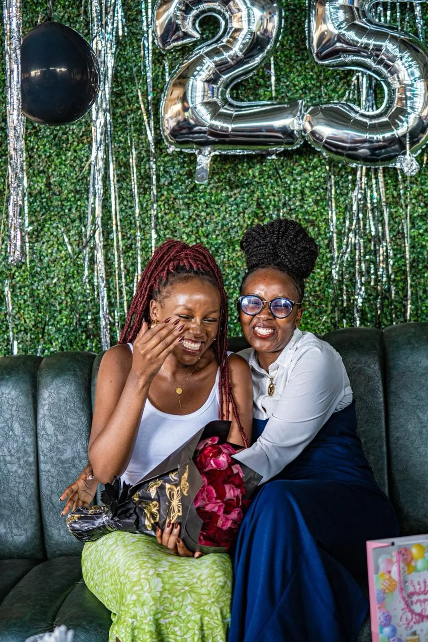 A birthday setup: balloon numbers, a greenery wall and flowers