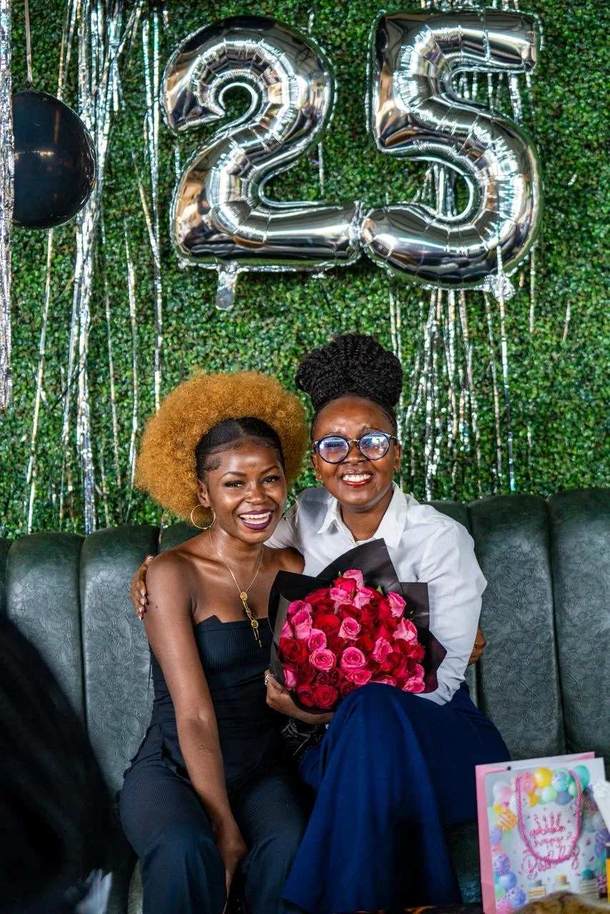 A birthday setup: balloon numbers, a greenery wall and flowers
