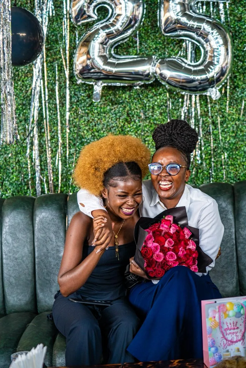 A birthday setup: balloon numbers, a greenery wall and flowers