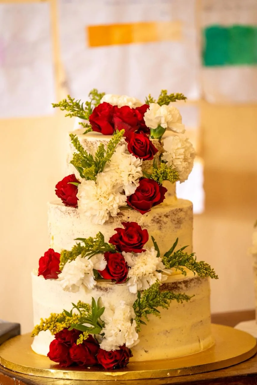 A tiered wedding cake dressed in fresh roses