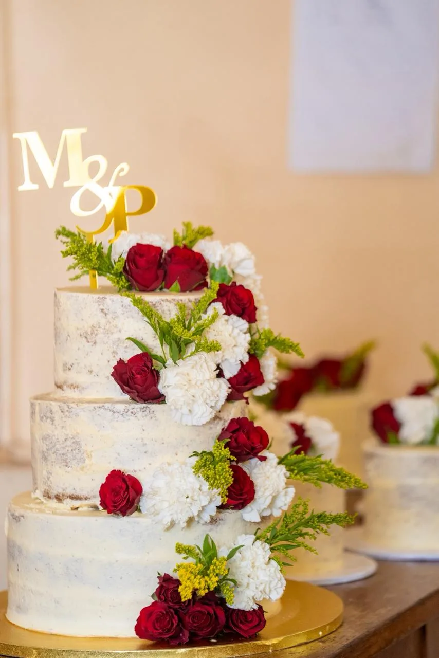A tiered wedding cake dressed in fresh roses