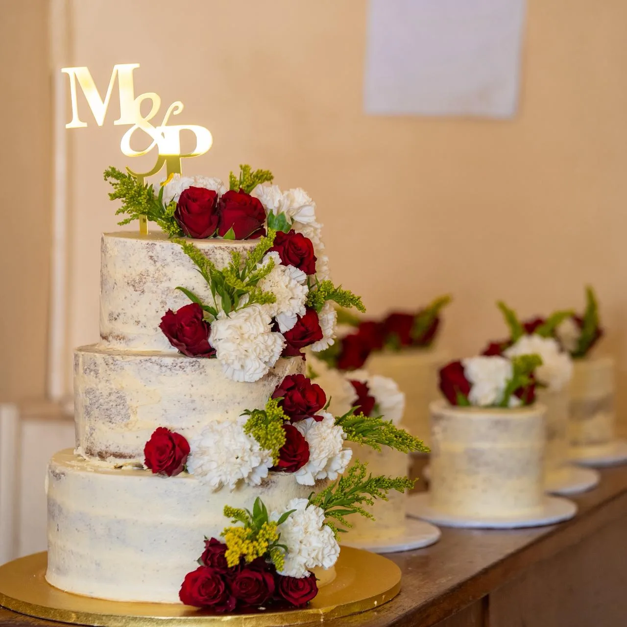 A tiered wedding cake dressed in fresh roses