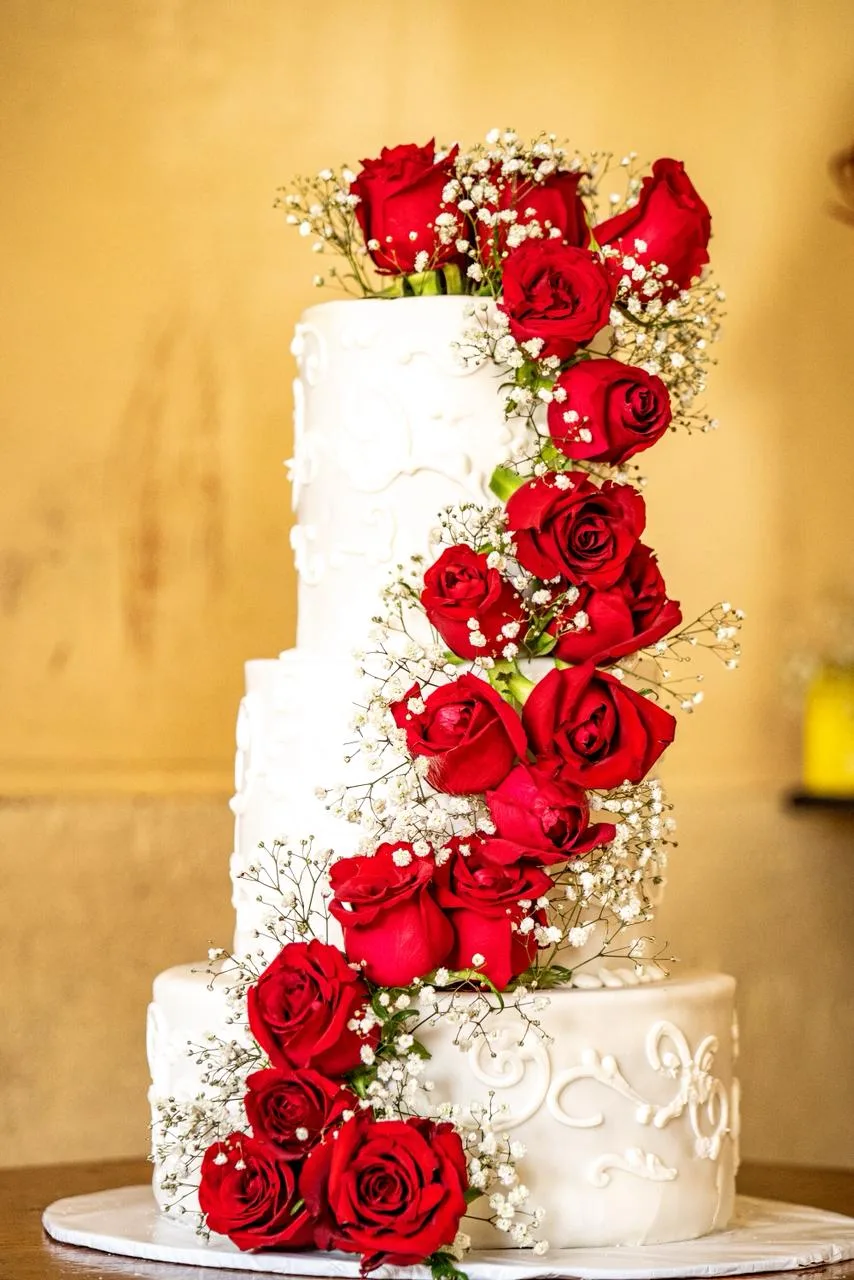 A tiered wedding cake dressed in fresh roses